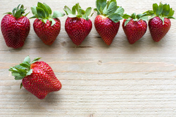 Row of fresh strawberries is on the wooden background