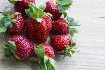 One pile of big fresh strawberries is on the wooden background