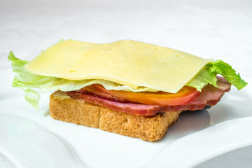 Delicious fast food. Sandwich with bacon, cucumber, cheese and herbs. Horizontal frame