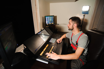 A lighting engineer works with lights technicians control on the concert show. Professional light mixer, mixing console. Equipment for concerts.