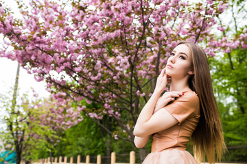 Naklejka na ściany i meble Spring beauty girl near Blooming sakura tree. Romantic young woman portrait
