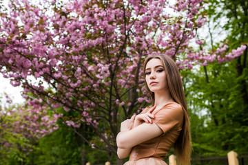 Naklejka premium Spring beauty girl near Blooming sakura tree. Romantic young woman portrait