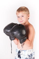 Little cute boy with boxing gloves celebrating his victory on the blank wall background