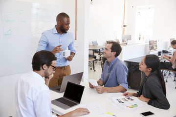 Young black man presenting an office meeting at a whiteboard