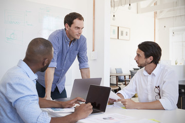 Fototapeta premium Three young men discussing business at an office meeting