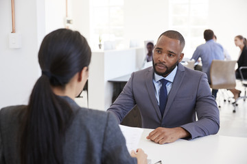 Businessman and woman sitting at desk in an open plan office