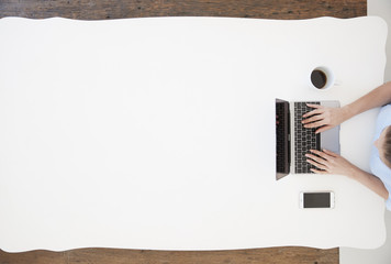 Young woman sitting at a desk and typing on laptop computer