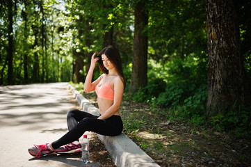 Fototapeta na wymiar Fitness sport girl in sportswear sitting at road in park with water at bottle, outdoor sports, urban style.