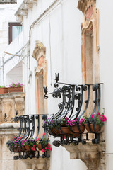 Martina Franca, Italy - May 25, 2017: Balconies with iron railing worked full of flowers