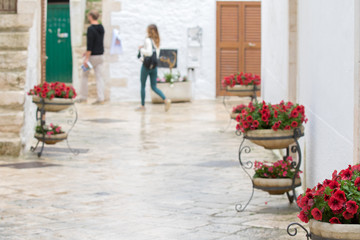 Locorotondo, Italy - May 25, 2017: A couple of tourists walking through the flowered alleys of the village