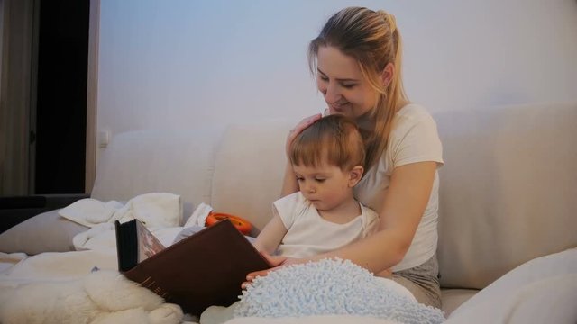 Cute toddler boy watching old family photographs in album with mother