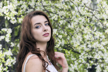Fototapeta premium Portrait of a girl surrounded by white blossoming apple trees