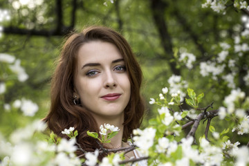 Portrait of a girl surrounded by white blossoming apple trees