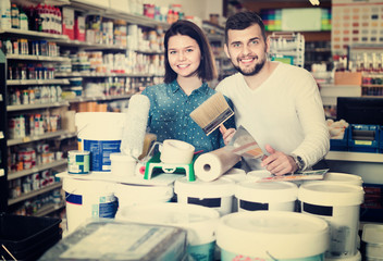 Fototapeta premium Couple purchasing tools for house improvements in paint supplies store