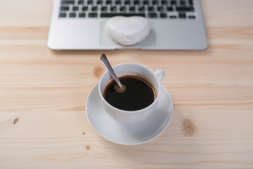 a Cup of coffee, gingerbread and a laptop on a wooden table