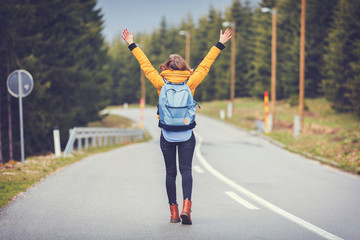 Girl enjoying alone on the road with arms wide open.