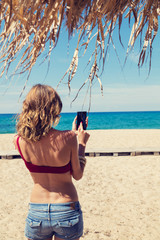 Girl holding a cellphone with sea/ocean background.