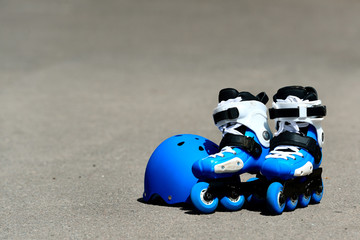 Roller inline skates with helmet in skate park on gray asphalt background