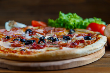 Delicious homemade pizza with mozzarella, ham, olives and fennel.