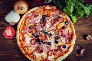 Delicious homemade pizza with mozzarella, ham, olives and fennel.