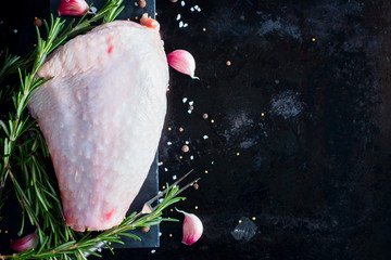 Fresh raw turkey thigh meat on a black background with spices and salt, top view, copy space