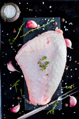 Fresh raw thigh meat on a bone with skin on a black background, top view