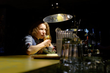 redhead girl sitting in bar (pub) drinking icy cocktail alone