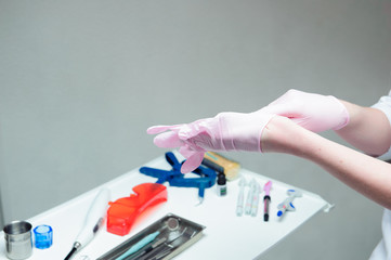 A young female doctor preparing herself for working, putting on protective gloves.