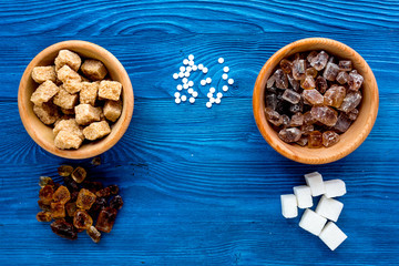 lumps of sugar with bowls sweet set on blue table background top view