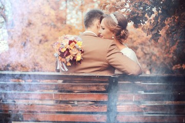 Newlyweds groom and bride walking in autumn park