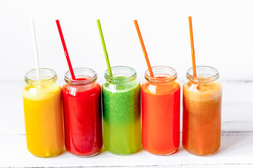 Fresh detox juices glass in row bottles on white background