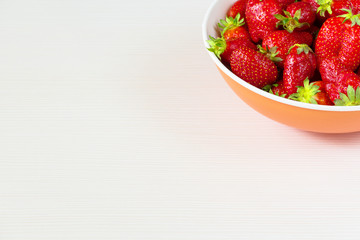 Red fresh strawberries in a bowl isolated on white background. Close up view.