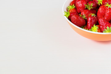 Red fresh strawberries in a bowl isolated on white background. Close up view.