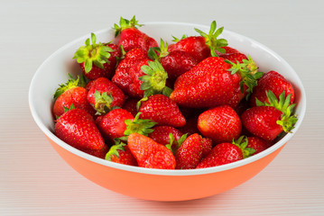 Red fresh strawberries in a bowl isolated on white background. Close up view.