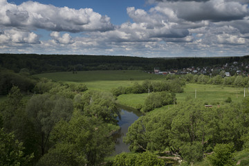 Green valley with a river and cumulus clouds on a sunny day