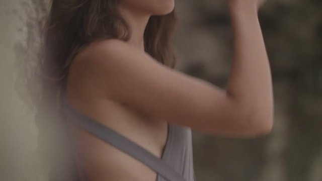 Seductive young woman in the swimsuit posing next to the rock