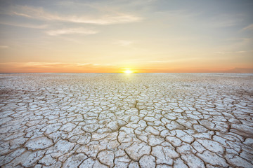 Soil drought cracked landscape on sunset sky