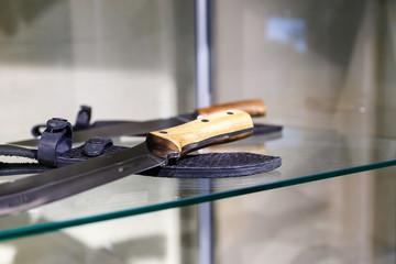 Hunting knives in harnesses lie on a shelf in a hunting shop