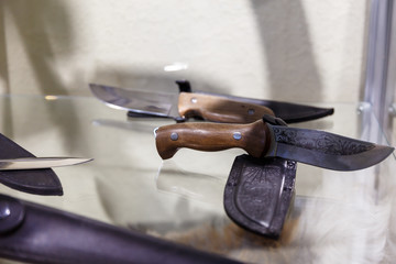 Hunting knives in harnesses lie on a shelf in a hunting shop
