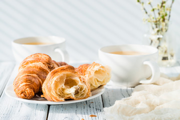 Croissants with cups of herbal tea on white rustic table