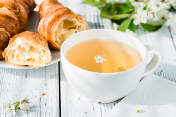 Cup of herbal tea and fresh croissants on plate