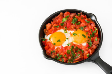 Shakshuka in iron frying pan isolated on white background. Typical food in Israel.

