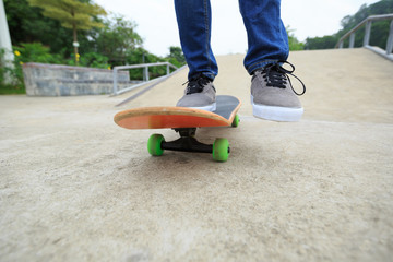 young skateboarder legs riding skateboard at skatepark