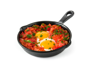 Shakshuka in iron frying pan isolated on white background. Typical food in Israel.

