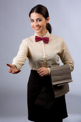 Cameriera molto carina con camicia beige e papillon rosso su sfondo chiaro, tiene il tovagliolo sul...