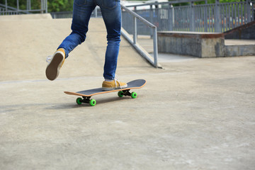 Fototapeta na wymiar young skateboarder legs riding skateboard at skatepark
