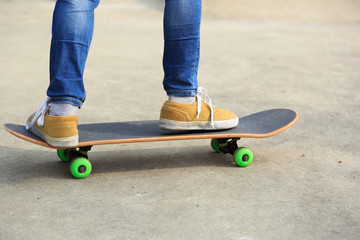 young skateboarder legs riding skateboard at skatepark