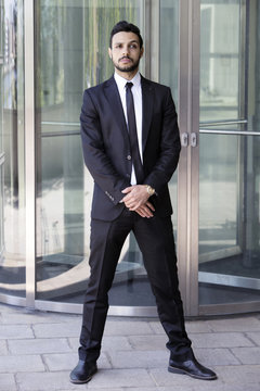man standing in a suit and tie in front of glass door