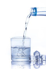 Water is poured into a glass with ice cubes