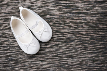 White baby shoe on wooden background , top view